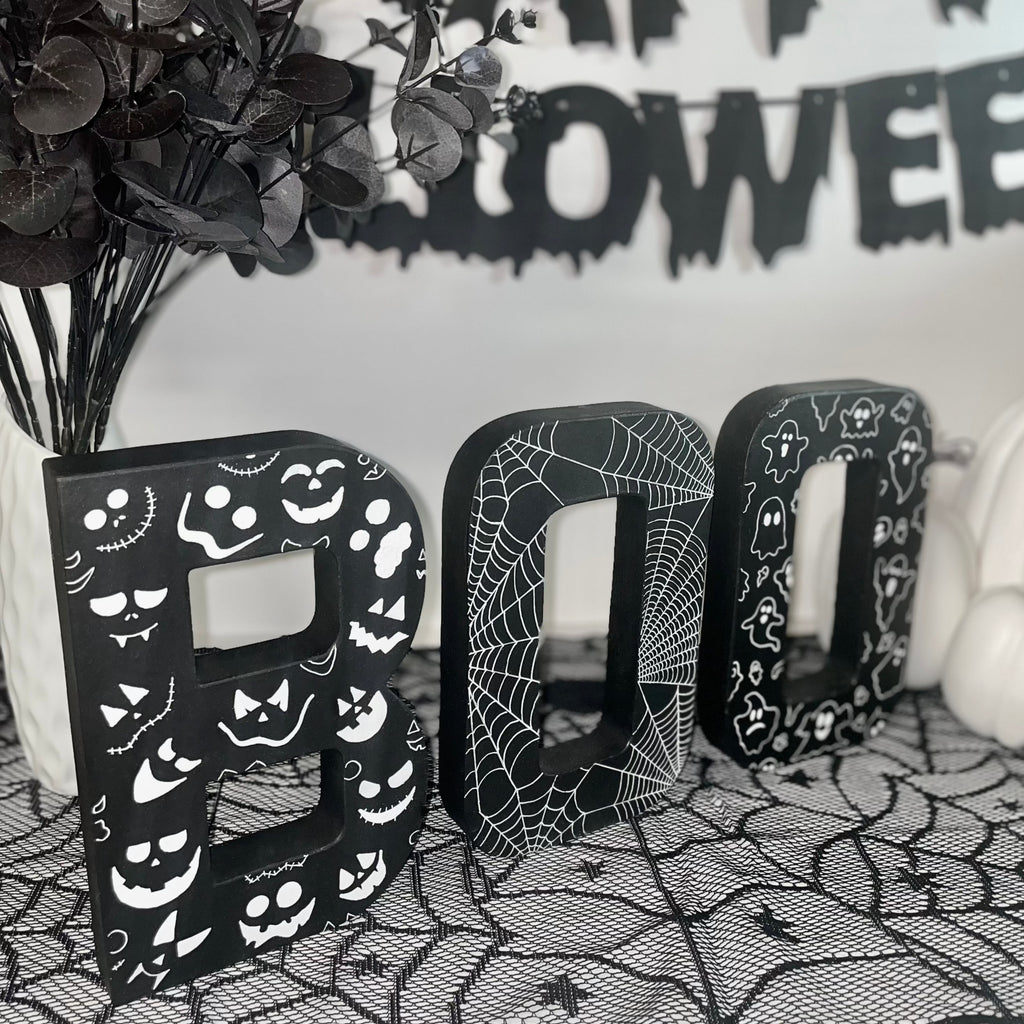 Black BOO Letters Decorated with white Pumpkin Faces, Spider Webs & Ghosts. Halloween Party Sign Decor. Freestanding Letters