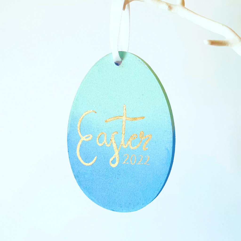 Mint & Blue Ombre Easter Egg Hanging Tree Decoration. Metallic Gold 'Easter 2022' on the front. Hung by white satin ribbon.